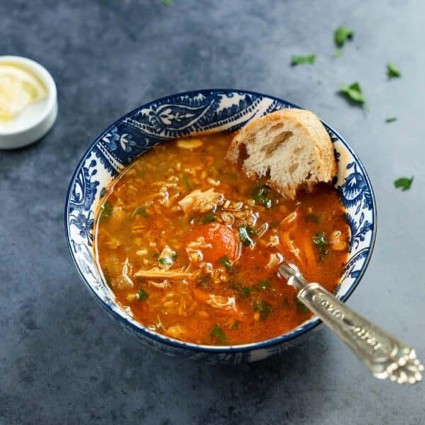 Kyllingsuppe med frikeh i blåmønstret bolle på mørk bakgrunn, sett fra øyenivå